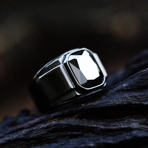 Men's vintage stainless steel ring with a faceted black onyx stone on a dark rock background