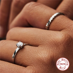 Macro shot of a 925 sterling silver ring with a sparkling round-cut zircon on finger