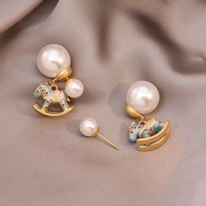 Detail of double pearl earrings with light blue enamel rocking horse charm on silk