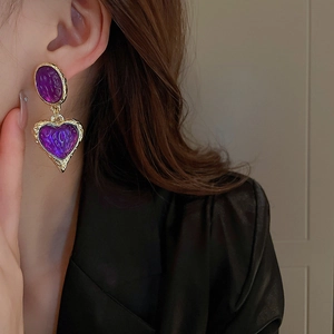 Detail of vintage heart earrings with purple resin and textured gold border on a model