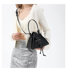 Detail of black triangular punk bag with silver cross charm and metal chain strap
