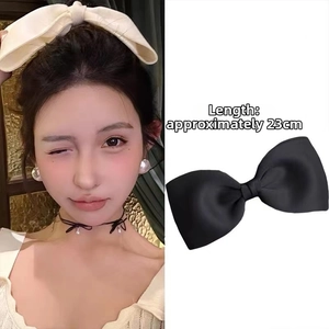 Detail view of a 23cm oversized black bow hair clip featuring an elegant satin finish