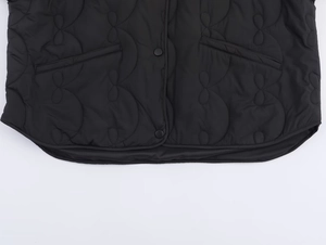 Détails de l'ourlet de la veste matelassée noire avec poches et boutons-pression