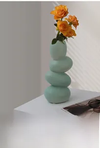 Détail du vase en céramique mate bleu sarcelle avec des roses sous des ombres de fenêtres