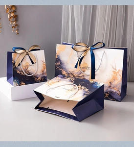 Royal blue marble gift bags in various sizes with elegant gold ribbon handles