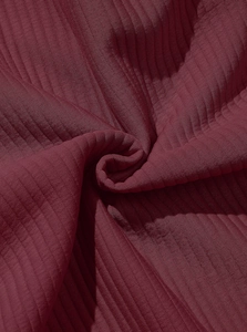 Close-up detail of burgundy ribbed knit fabric texture on a long sleeve polo shirt