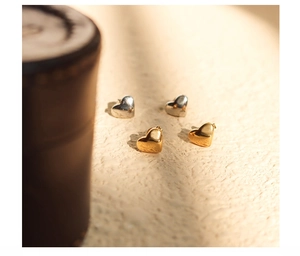 Macro detail of elegant gold and silver heart-shaped stud earrings in a glossy finish