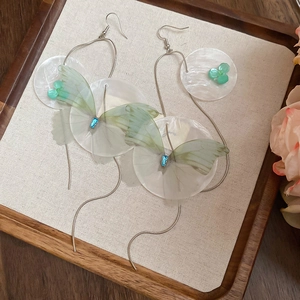 Detail of floral geometric resin drop earrings with white shell texture and green butterfly wings
