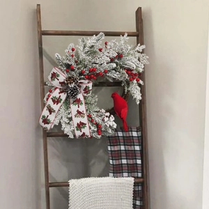 Detail of Christmas wreath with cardinal bird, frosted pine needles and decorative ribbon