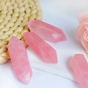 Colonnes hexagonales en quartz rose naturel sur tissu blanc avec décor floral