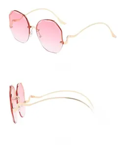 Detail of rimless sunglasses with pink gradient lenses and gold wave-shaped temples