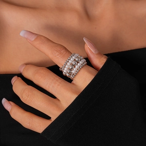 Macro shot of layered silver metal beads and white pearls on an elastic stacked ring