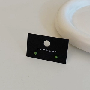 Detailed view of green bean-shaped stud earrings on a black jewelry display card