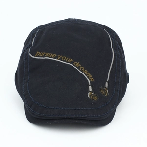 Detail of black cotton beret featuring golden embroidery of pursue your dreams and headset