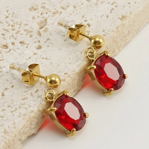 Elegant gold titanium steel earrings with oval red zircon stones on a stone pedestal