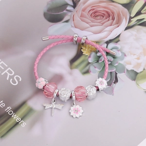 Pink woven charm bracelet with crystal beads and butterfly dragonfly flower pendants
