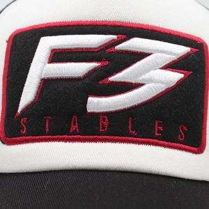 Detailed close-up of F3 Stables 3D embroidery and red stitching on a cotton mesh cap