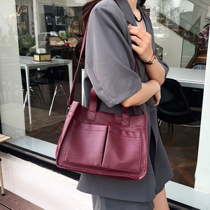 Detail of burgundy tote bag with front pockets and retro lychee texture on shoulder strap