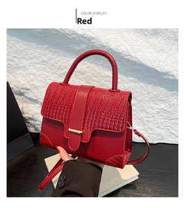 Detail der roten Handtasche mit Krokodilprägung, Goldbeschlägen und Rundgriff