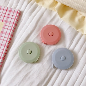 Flat lay of pink, green and blue mini 1.5m retractable soft measuring tapes on white fabric