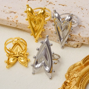 Detail view of gold and silver heart-shaped rings with beaded edges on a stone surface