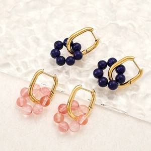 Golden U-shaped earrings with natural blue and pink stone beads on a textured surface