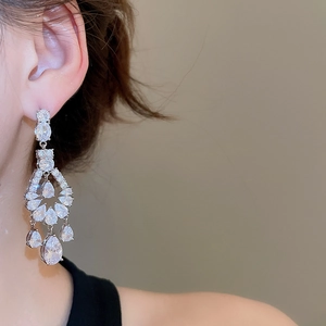 Detail of silver drop earrings with zircons on model for an elegant evening look