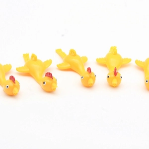 Detailed close-up of 5 yellow rubber slingshot chickens arranged on a white background