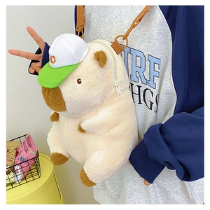 Detail showing the plush capybara bag with a mini baseball cap and nylon shoulder strap