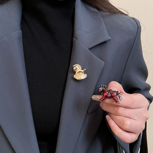 Détail de broches cheval de luxe avec finition émail et cristaux rouges sur un revers