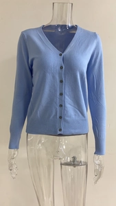 Detail van het hemelblauwe vest met V-hals voorzien van donkere knopen en geribbelde manchetten
