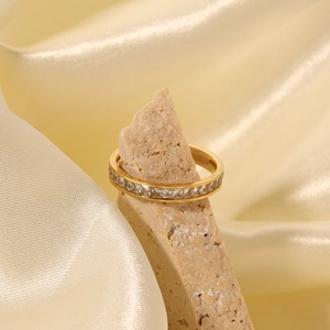 Elegant gold titanium steel ring with cubic zirconia stones displayed on a natural stone