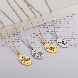 Close-up of oval stainless steel pendants with engraved flower and holly leaf patterns