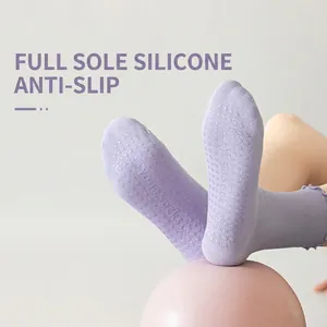 Purple yoga socks with non-slip silicone grips and ruffle cuffs on a pink ball