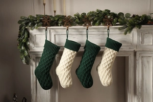 Detail von gestrickten Weihnachtsstrümpfen in Dunkelgrün und Elfenbein am Kamin
