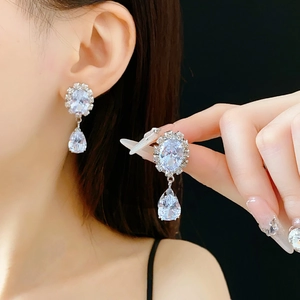 Macro detail of silver teardrop earrings with sparkling zircon stones on a model