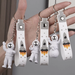 Three white and grey astronaut keychains with rocket straps held by hand display