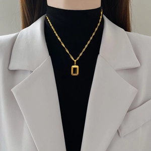 Minimalist square black pendant necklace in gold titanium steel worn on black turtleneck