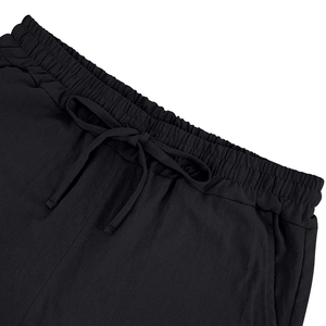 Detail of black linen shorts featuring elastic drawstring waist and side pocket texture
