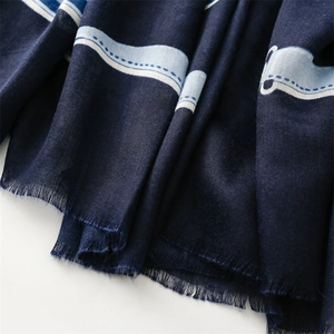 Detailed macro view of dark blue scarf fabric texture with soft tassels and woven patterns