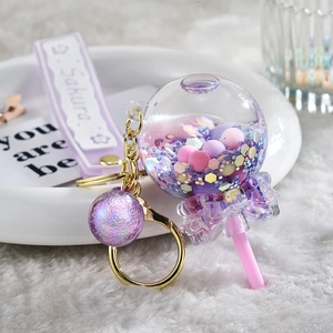 Detailed macro view of cute Sakura quicksand lollipop keychain with purple beads and glitter