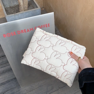 Close-up of white quilted cosmetic bag with red rabbit embroidery and soft cotton texture