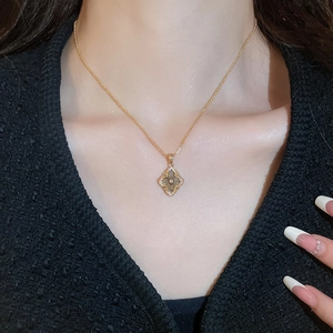 Close-up of a gold-plated vintage clover pendant necklace on a model with sparkling diamond