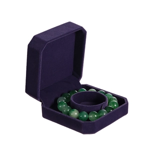 Detail of dark purple velvet octagonal jewelry box holding a green beaded bracelet