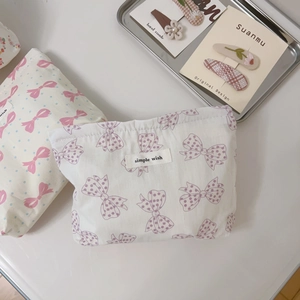 Close-up of white cotton makeup bags with pink and purple bow patterns and zip closure