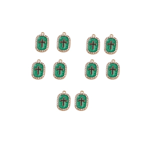 Detailed view of ten gold cross pendants with green enamel and sparkling rhinestones