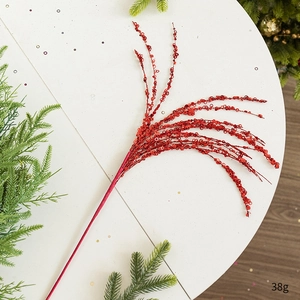 Close-up of red sequined Christmas branch decoration on white table with pine needles