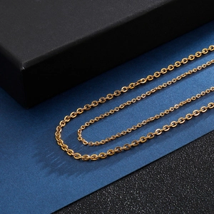 Detail shot of golden stainless steel O-chain necklaces layered on a dark blue background