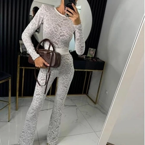 Detail of white floral lace long sleeve jumpsuit with slim fit and elegant see-through patterns