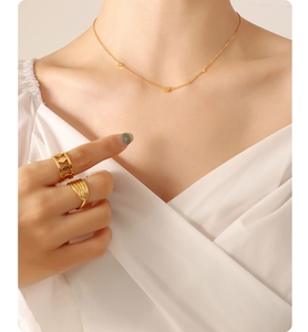 Detail of 18K gold-plated necklace and rings worn by a model in soft warm lighting